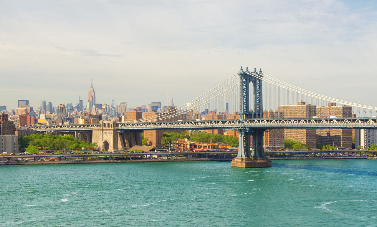 Foto. Vista diurna da Ponte Manhattan, em Nova York, com a cidade ao fundo. Foto. Vista diurna da Ponte Manhattan, em Nova York, com a cidade ao fundo.